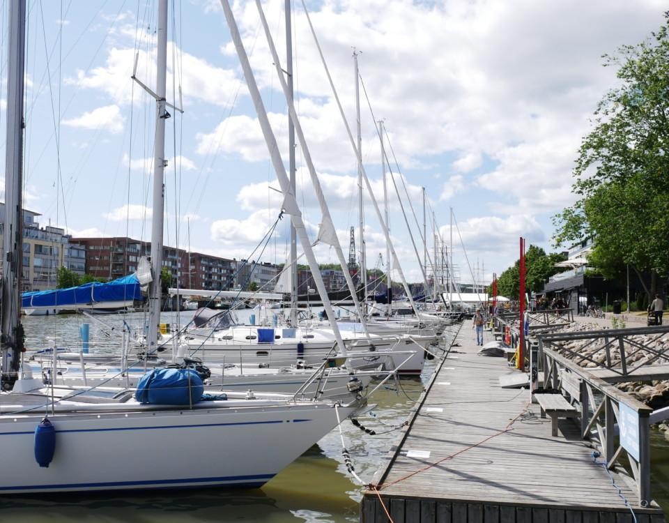 Stora segelbåtar på rad vid brygga.