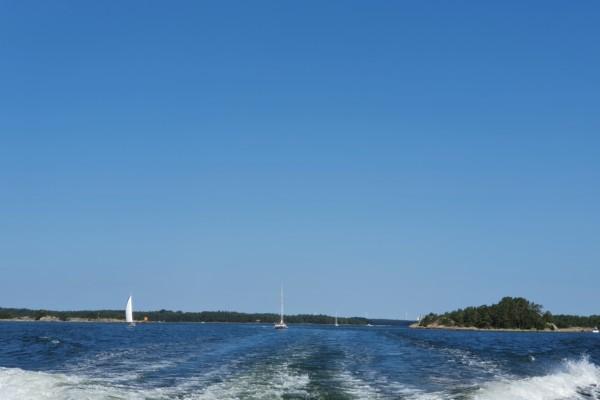 Några segelbåtar syns på avstånd i havet, lummig ö på håll.