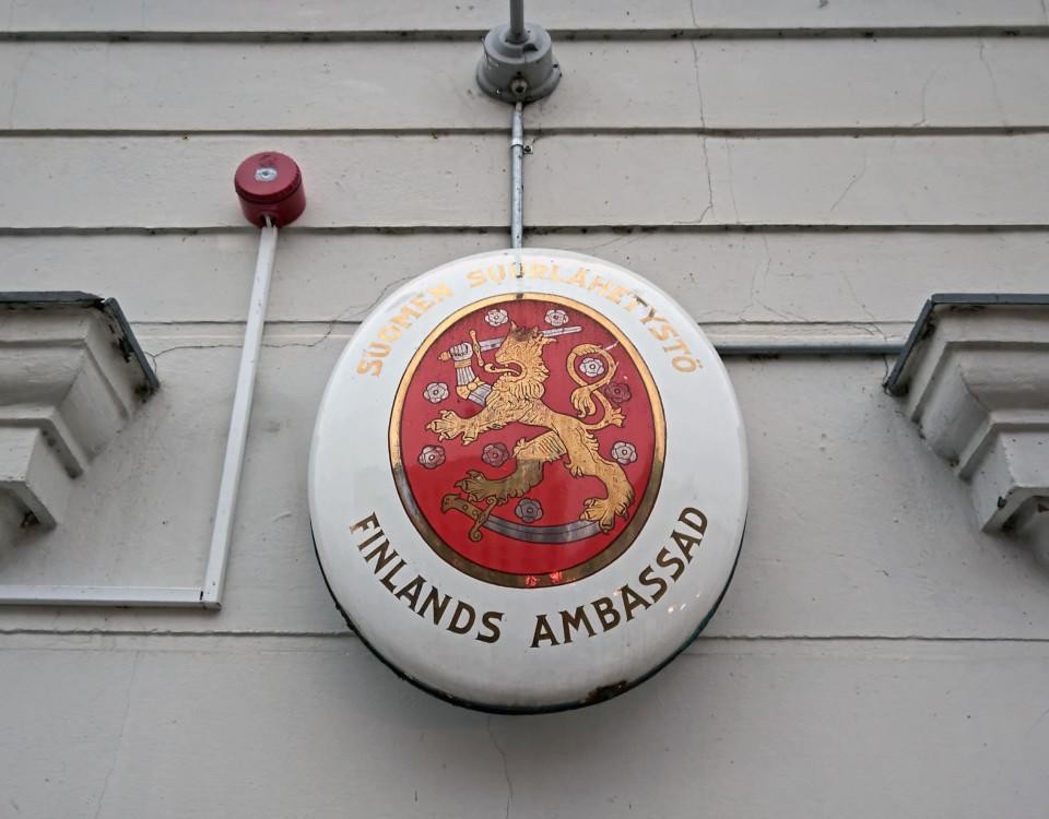 Ett märke med texten Finlands ambassad på väggen.