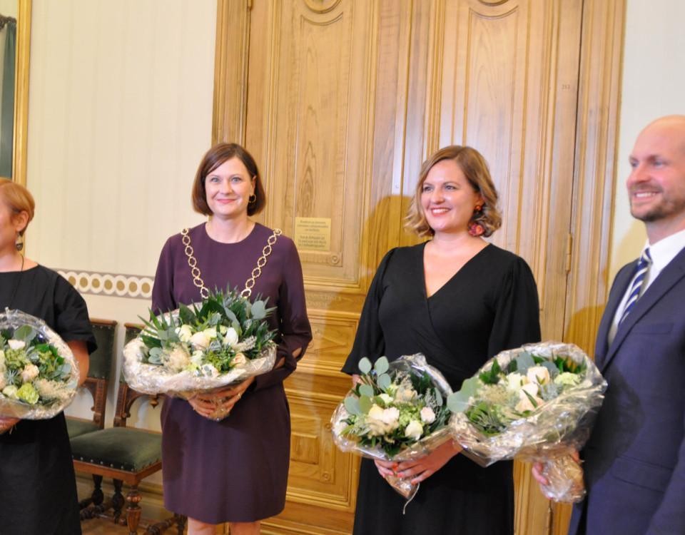 Tre kvinnor och en man med blommor i händerna