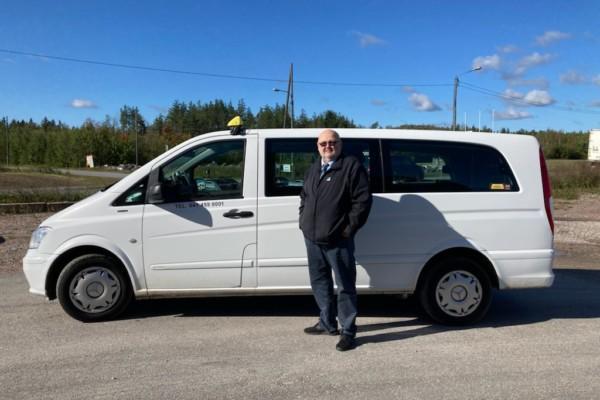 En taxichaufför framför sin bil