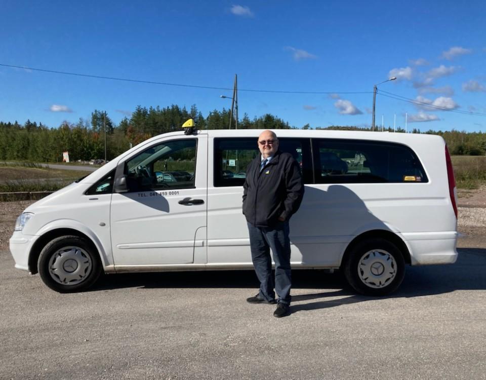 En taxichaufför framför sin bil