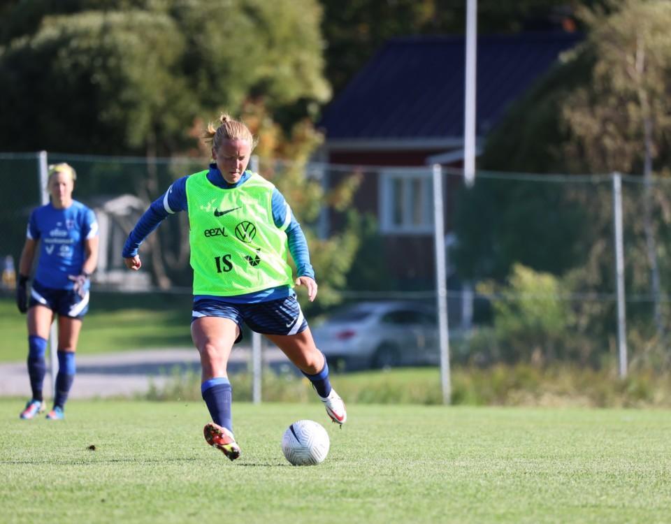 kvinna springer med fotboll på fotboll på plan