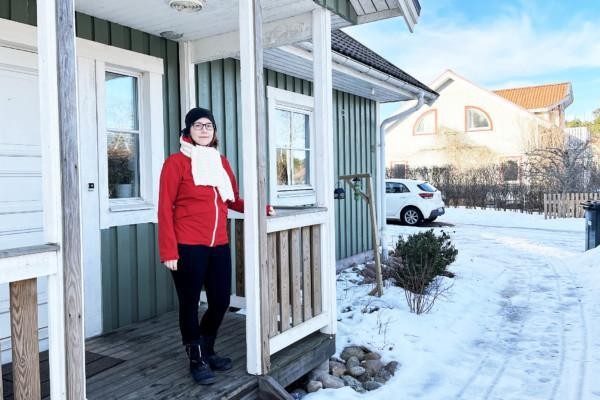 Kvinna i röd jacka på trappan till ett hus.