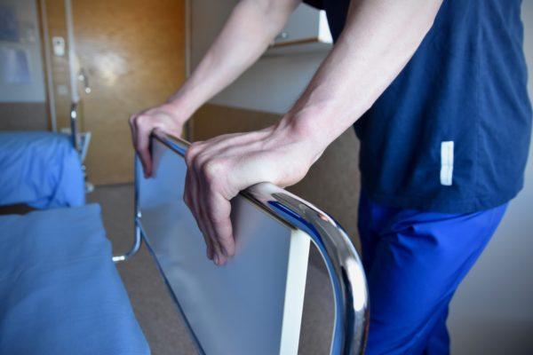 en vårdares händer på en sjukhussäng