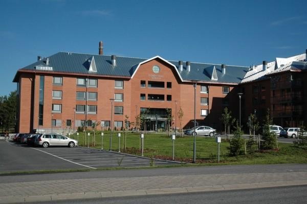 Sjukhusbyggnad i tegel med parkeringsplats framför