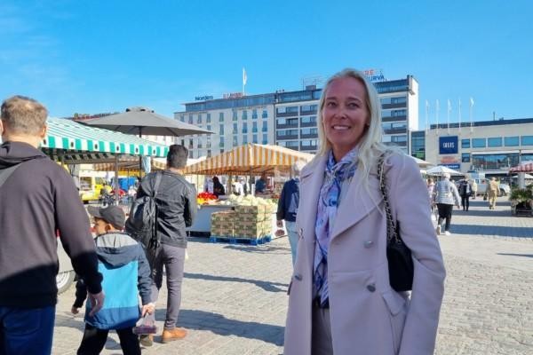 kvinan i rosa kappa på ett torg, blå himmel i bakgrunden