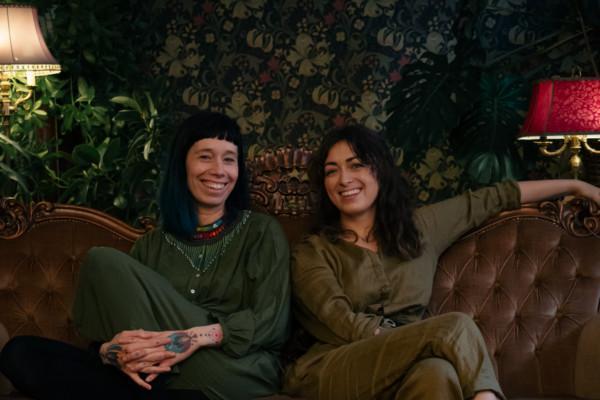 Två leende kvinnor sitter i en soffa