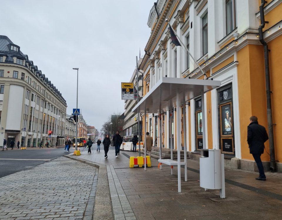 En busshållplats vid torget utanför en byggnad.