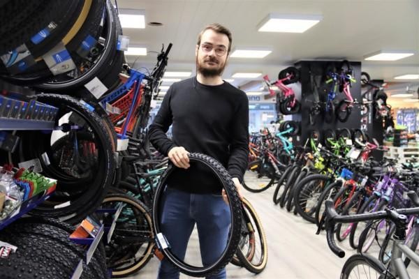 En man håller upp en cykelring i en affär.