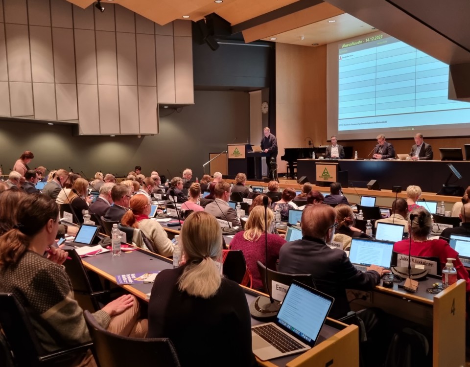 politiker i stort auditorium, fotade bakifrån