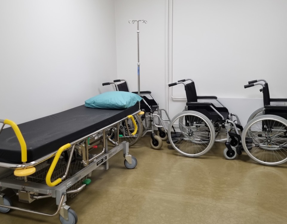 en sjukhusbrits och två rullstolar i ett väntrum