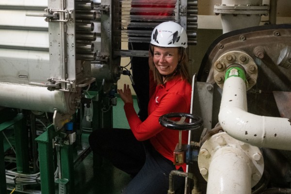 En kvinna med hjälm i ett maskinrum på ett fartyg.