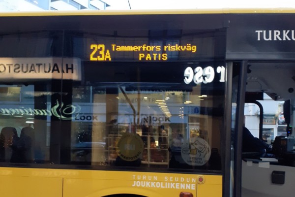 närbild av gul bussdörr som speglar sig i fönster