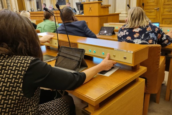 kvinna fotad bakifrån när hon röstar på ett politiskt möte genom att trycka på en knapp