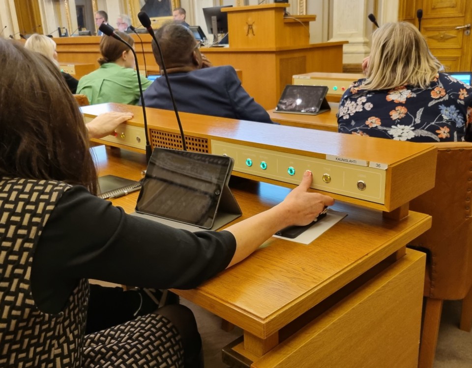 kvinna fotad bakifrån när hon röstar på ett politiskt möte genom att trycka på en knapp