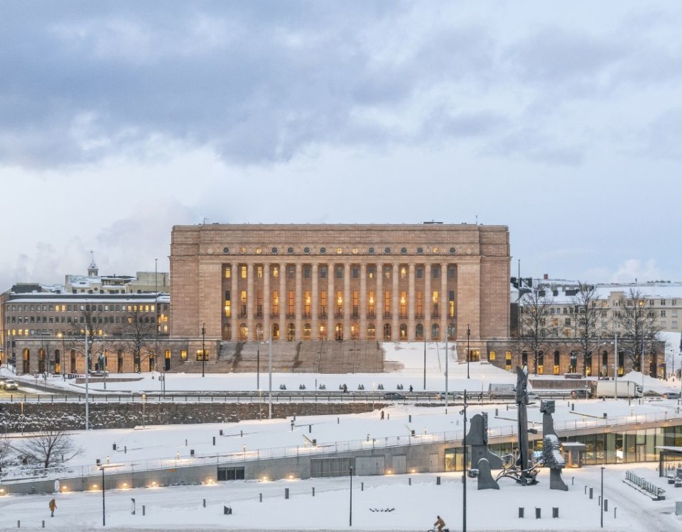 fyrkantigt stort granithus med pelare och snö. Finlands riksdagshus