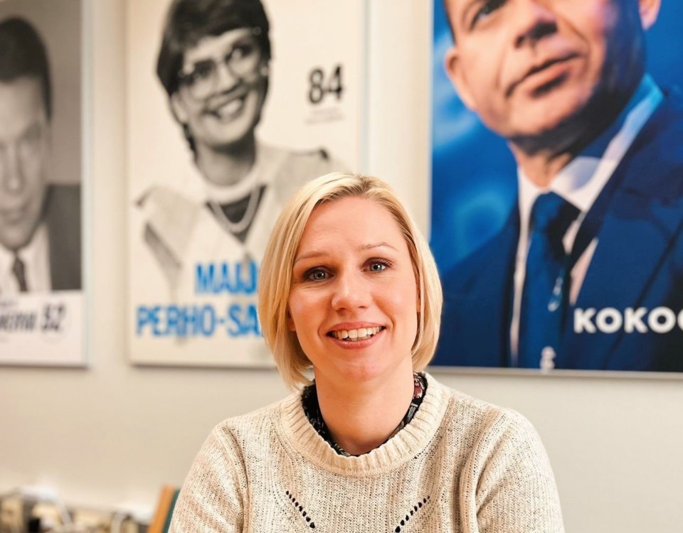 kvinna med ljust hår framför partiledaraffischer