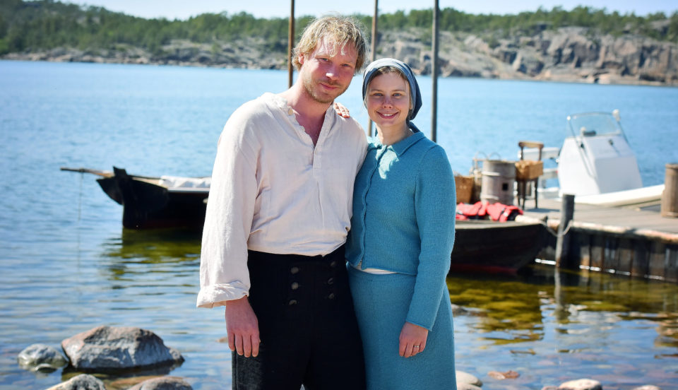 Ett par håller om varandra i skärgårdsmiljö en sommardag