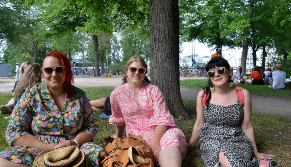 Tre kvinnor sitter på gräset i en park.