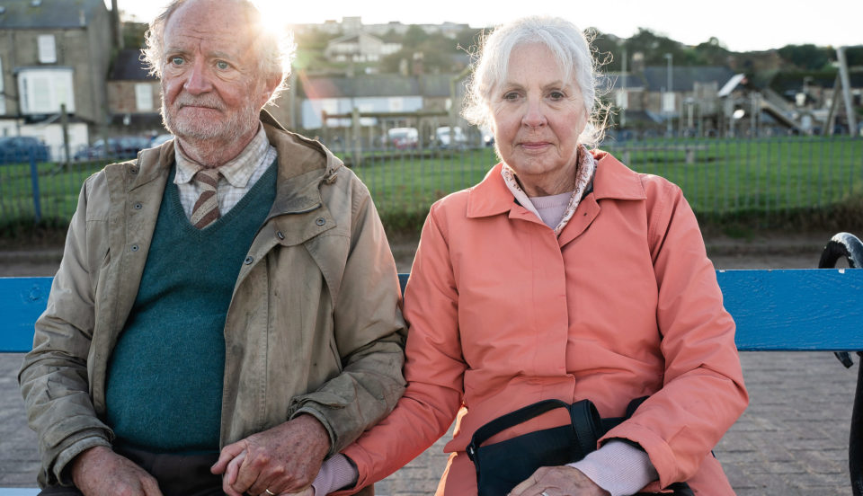 Ett pensionärspar sitter och håller händer