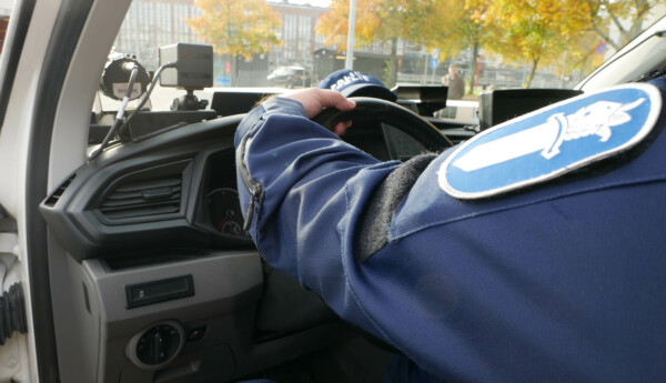 en polis sitter bakom ratten i en polisbil