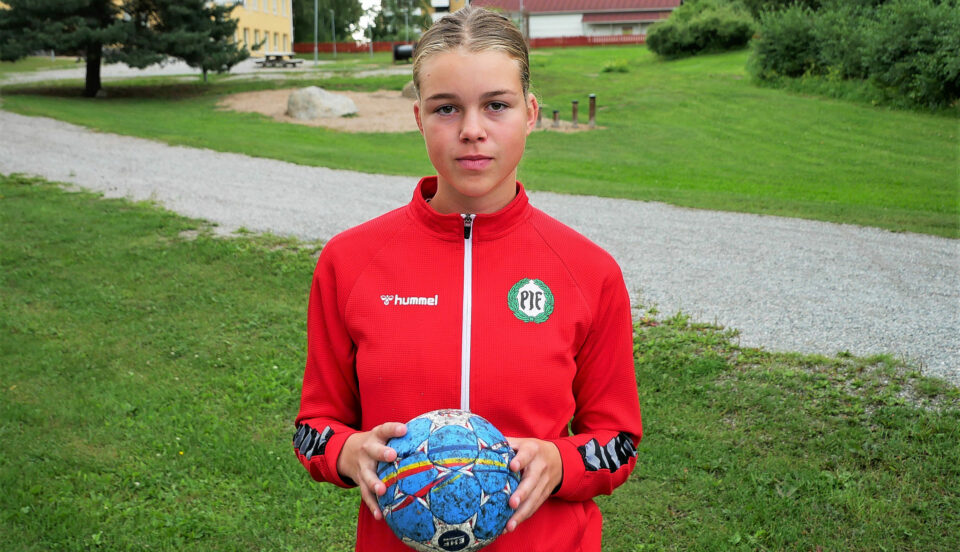 En ung flicka med sportkläder och en handboll i handen.