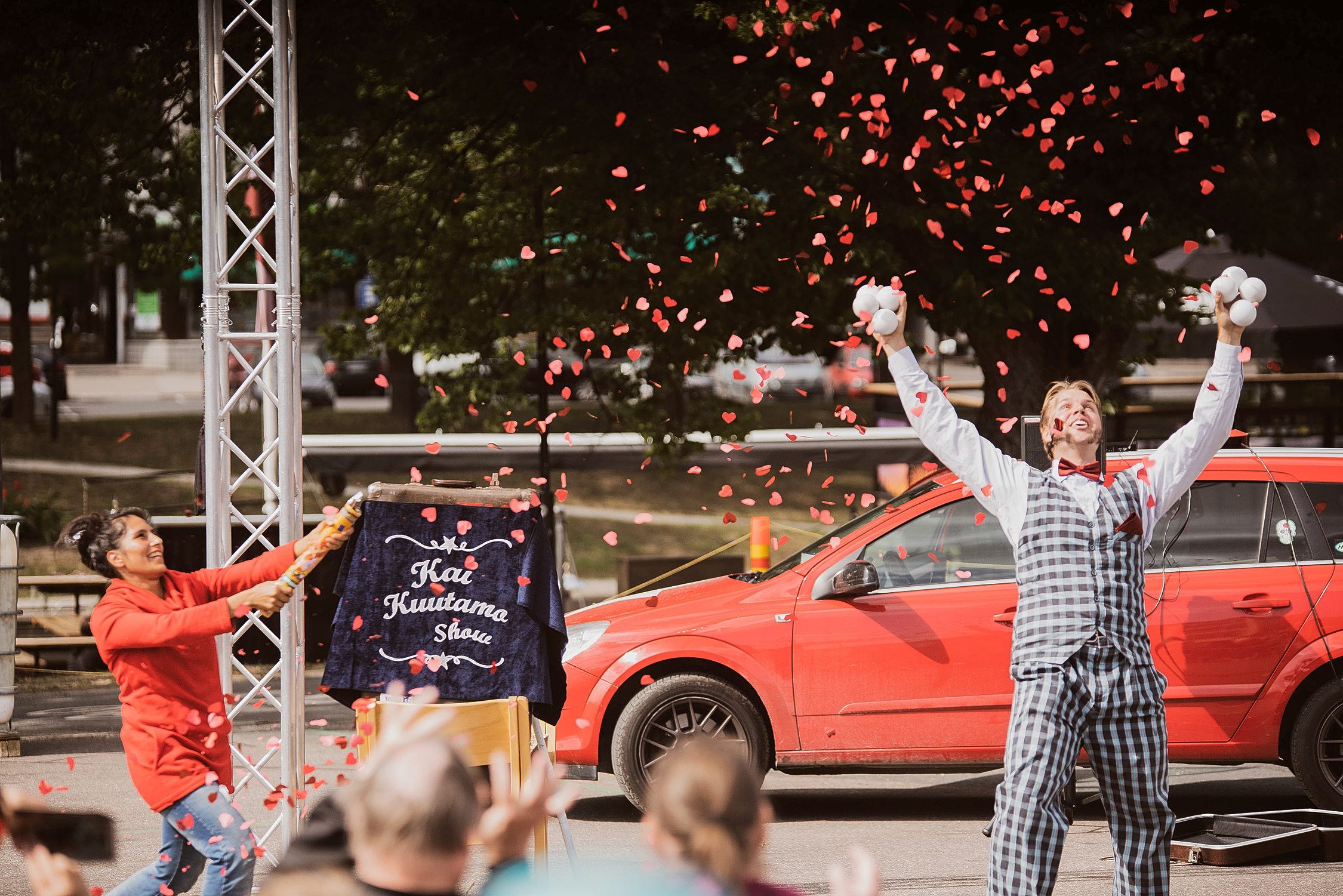 En jonglör står med bollarna i handen och poserar framför publiken.