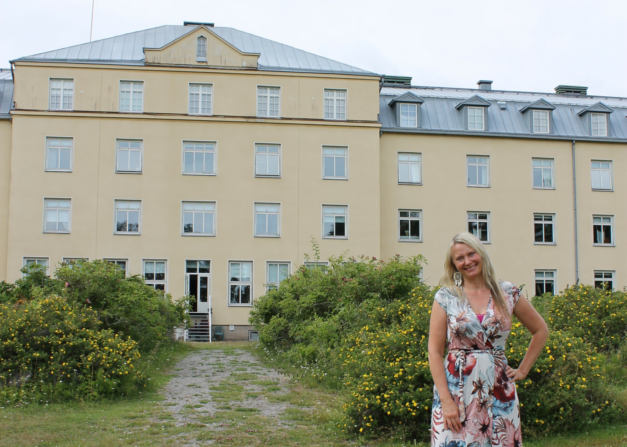 Kvinna står utanför ett stort gult hus i Knipnäs, Ekenäs.