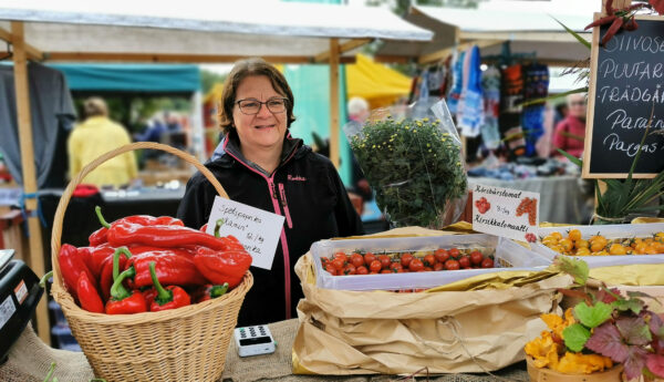 Kvinna bakom försäljningsstånd med grönsaker