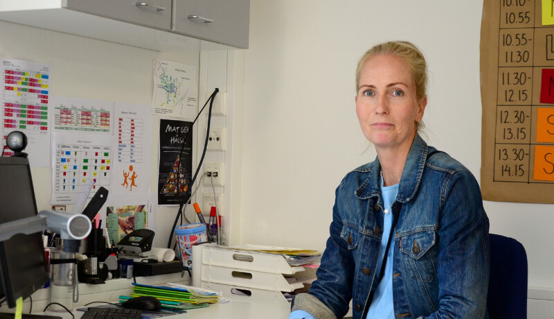 Ljushårig kvinna i jeansjacka sitter vid arbetsbord