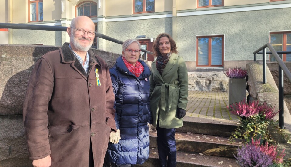 En man och två kvinnor står på en trappa framför en gammal stenbyggnad.