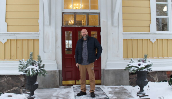 En man står utanför ett gult trähus. Huset ligger i Seminarieparken i Ekenäs. Betesda Chruch har nyligen flyttat in i huset. Mannen är ledande pastor för Betesda Church.